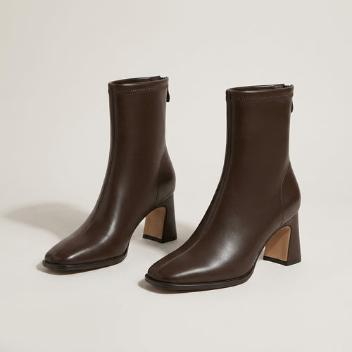 A pair of dark brown ankle boots with block heels and square toes, displayed on a clean, light beige studio background.